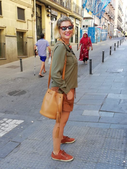 Chica usando bermudas con sudadera verde olivo con bucket bag color camel