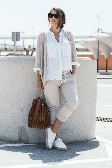 Chica usando conjunto de joggers y suéter color beige con camisa blanca y bucket bag de gamuza color café