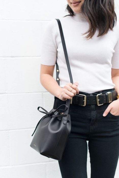 Chica usando top blanco con jeans negros y bucket bag color negro