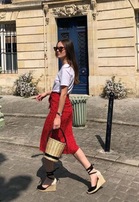 Chica usando falda roja, playera blanca, alpargatas negras y bucket bag de mimbre