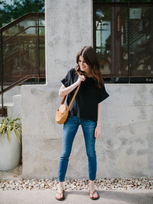 Chica camina en la calle con jeans, blusa negra y flip flops