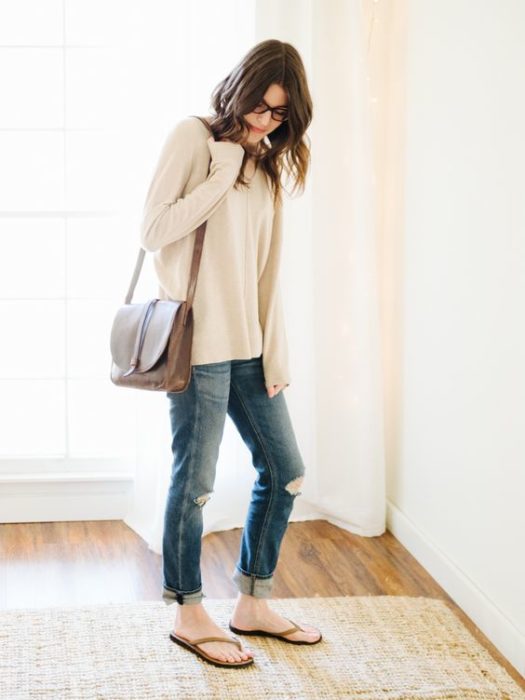 Chica con sudadera larga blanca, bolsa café, jeans y flip flops