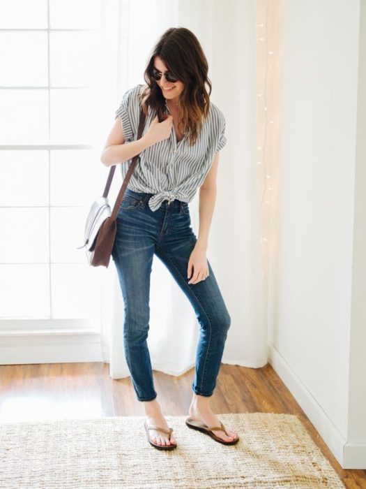 Chica posando con jenas oscuros, blusa gris y flip flops negros