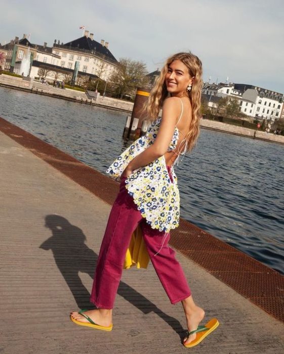 Chica rubia caminar por un lago con pantalón rosa y flip flops