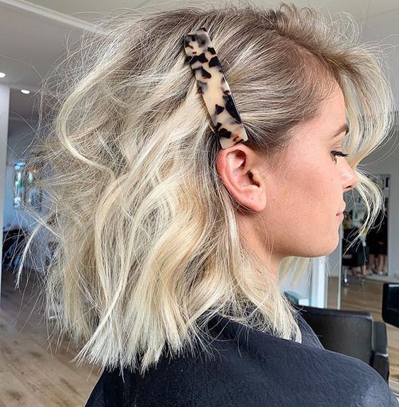 Chica rubia de cabello corto con broche grande en el costado