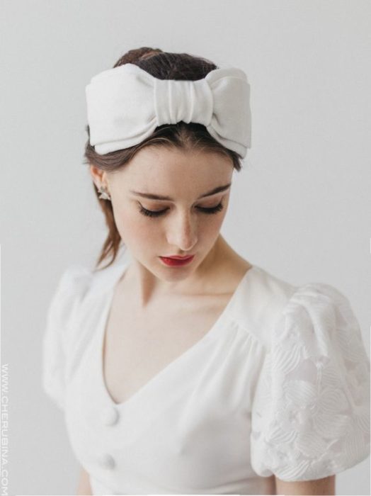 Chica de piel clara con blusa blanca y diadema blanca de moño