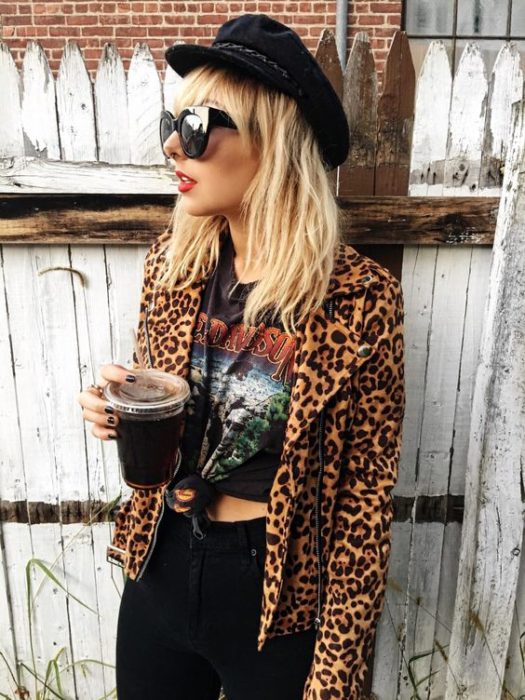 Chica rubia con rubia con gorro negro, saco de animal print y blusa negra