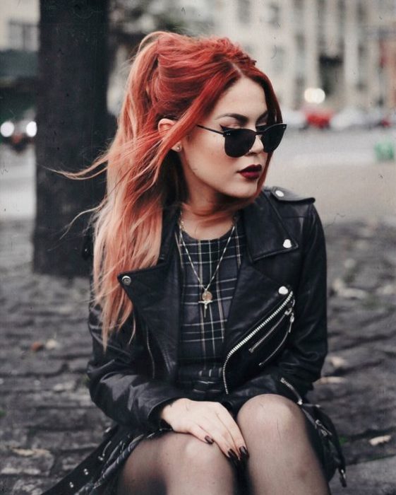 Chica de cabello rojo con lentes de sol y outfit negro