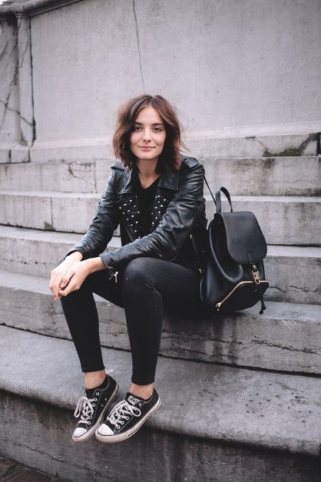 Chica con outfit negro y converse negros sentada en escalones