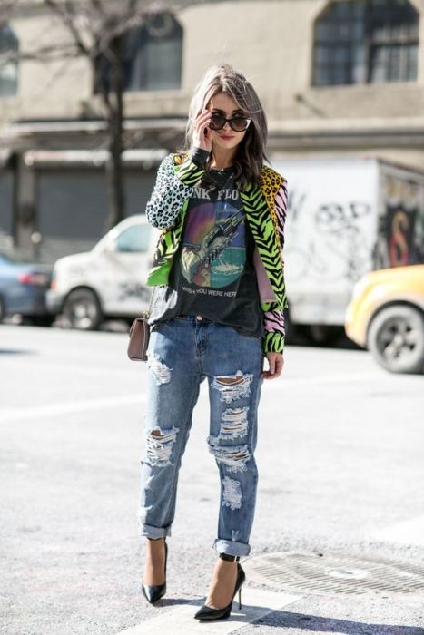 Chica con jeans rotos, blusa negra y saco de animal print color verde