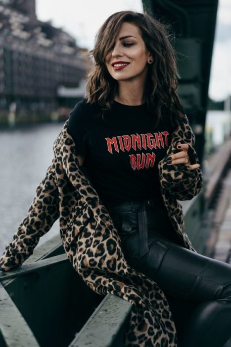 Chica con outfit negro y abrigo de leopardo sentada