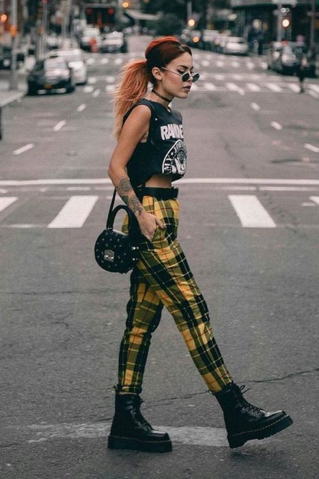 Chica camina por la calle con blusa negra y pantalón amarillo de cuadros