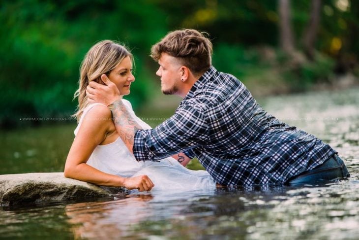 Sesión de fotos de pareja en el agua mientras se abrazan 