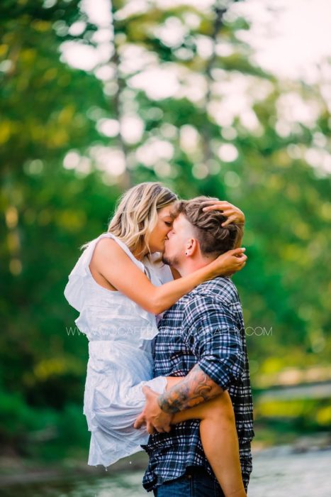 Pareja de novios durante una sesión de fotos mientras están abrazados y se besan 