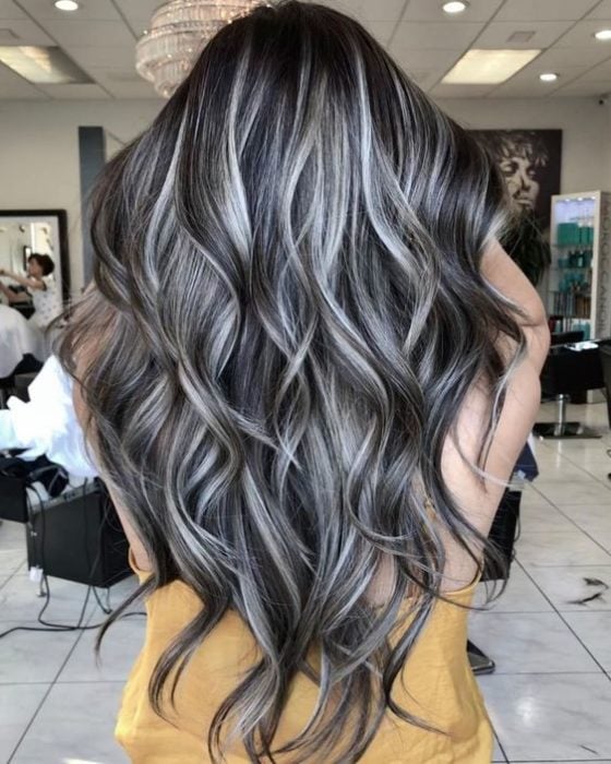 Chica de espaldas mostrando su largo cabello teñido con silver highlights