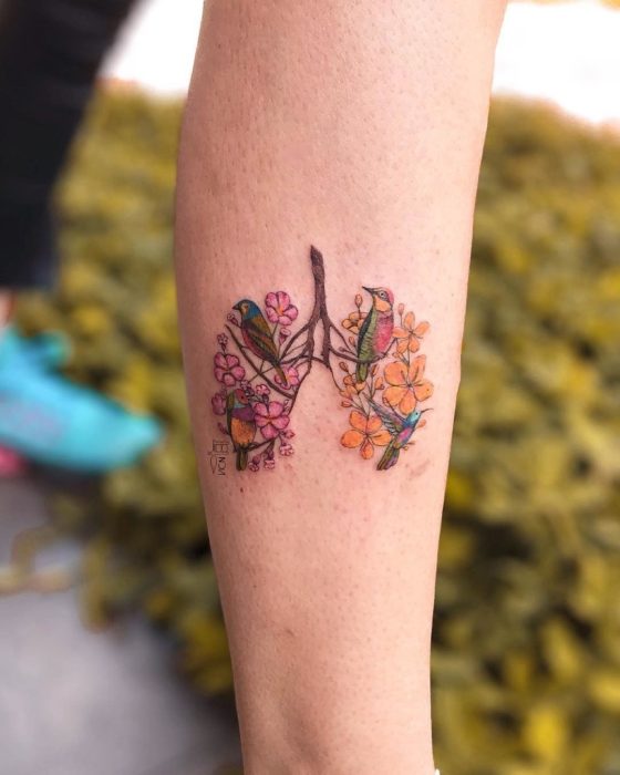 Tatuaje de flores en el antebrazo donde es la silueta de unos pulmones que llevan dibujados varias plantas