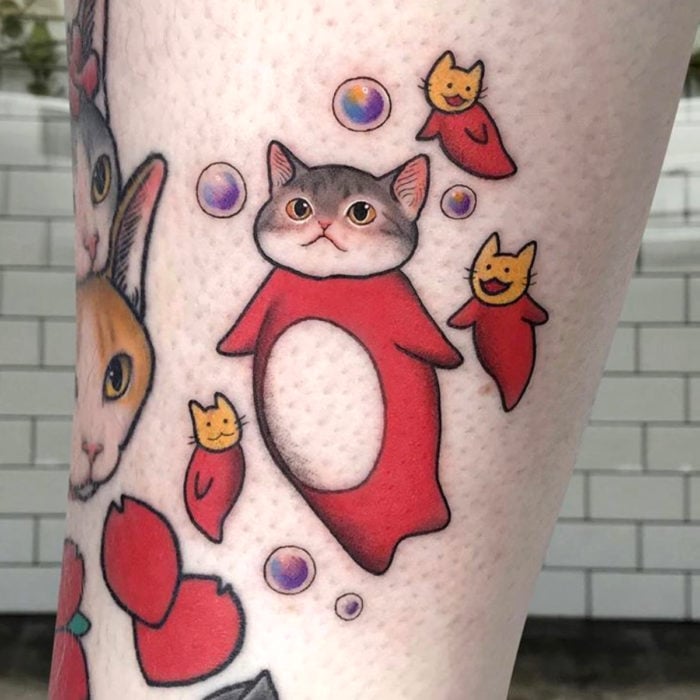 Tatuajes de gatos; tatuaje en la pierna de peces estilo Ponyo de estudio Ghibli con cabeza de felino tierno