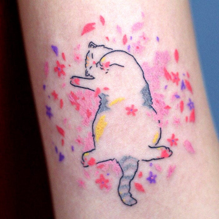 Tatuajes de gatos; tatuaje de felino acostado en flores