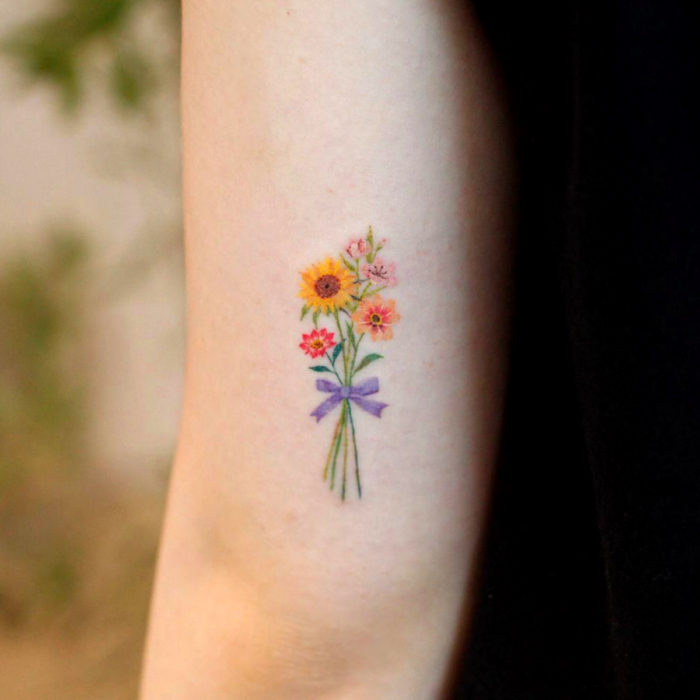 Tatuaje de girasoles miniatura en colores pastel en el brazo