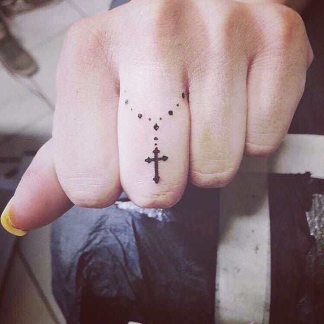 Chica con un rosario tatuado en el dedo medio