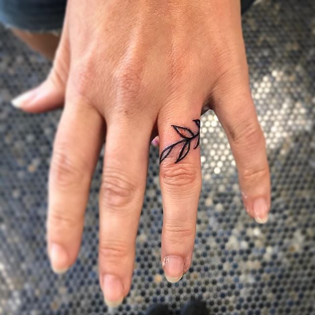 Chica con un anillo de hojas tatuado en sus dedos 