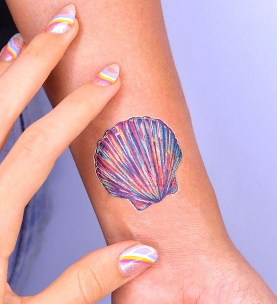 Tatuaje en forma de concha marina con efecto metalizado en tono amarillo, azul, rosa y morado