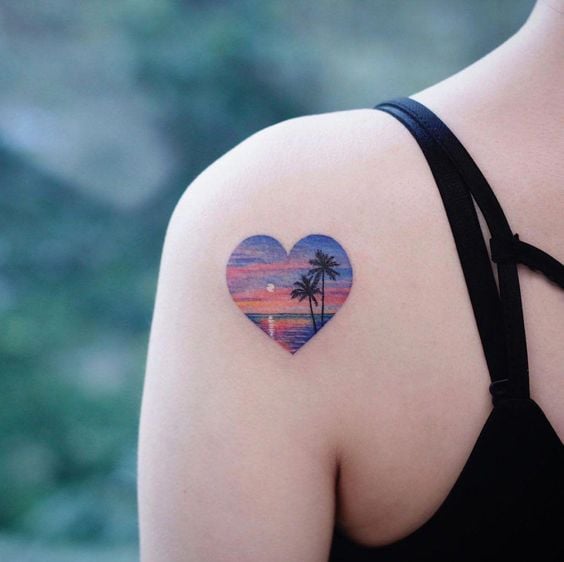 Chica con tatauje en forma de corazón con dibujo del mar en un atardecer en el interior