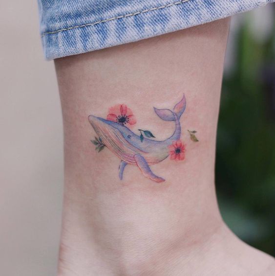 Tatuaje de ballena en efecto acuarela con colores pastel azul, rojo y rosa
