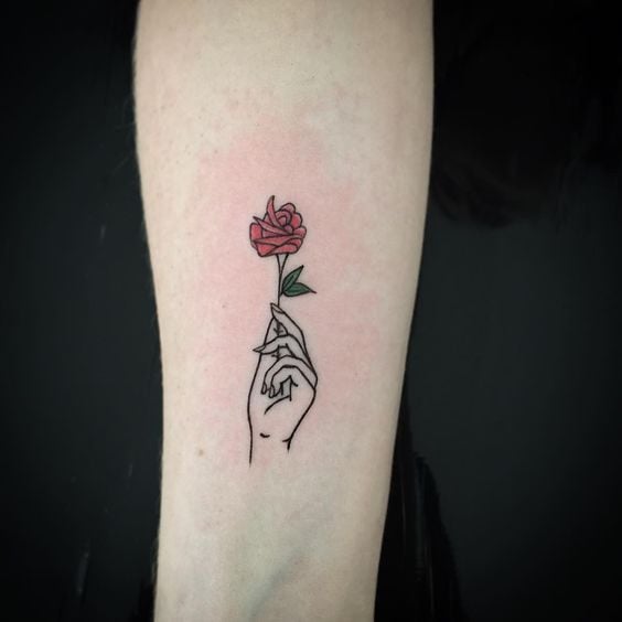 Tatuaje de mano sosteniendo una rosa en el bazo