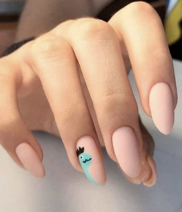 Diseño de manicure sencillos, femeninos y naturales; uñas largas en forma de almendra pintadas con esmalte nude y dibujo de un dinosaurio azul