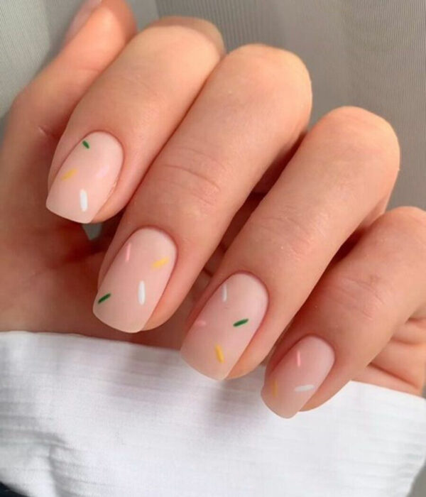 Diseño de manicure sencillos, femeninos y naturales; uñas medianas cuadradas pintadas con esmalte nude y chispas de chocolate verdes, blancas, rosas y amarillas