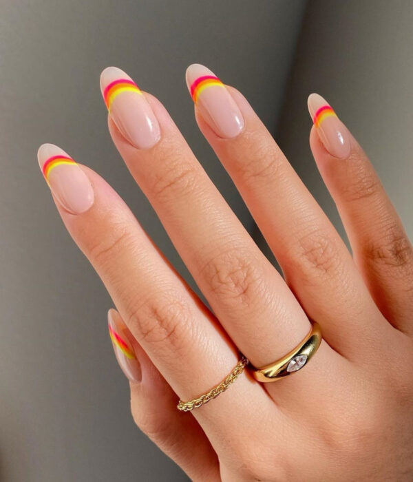Diseño de manicure sencillos, femeninos y naturales; uñas largas en forma de almendra, pintadas con esmalte nude y líneas de colores rosa, anranjado y amarillo