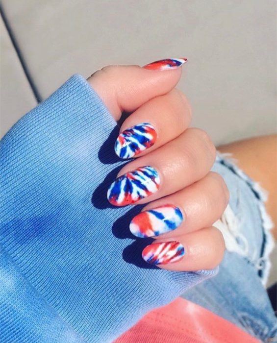 Manicura estilo tie dye en fondo blanco con azul rey y rojo