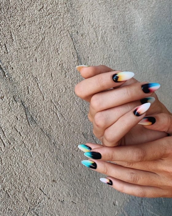 Manicura estilo tie dye con base negra y diferentes colores