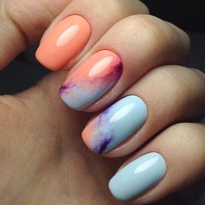 Manicura estilo tie dye en color melón y azul con detalles morados