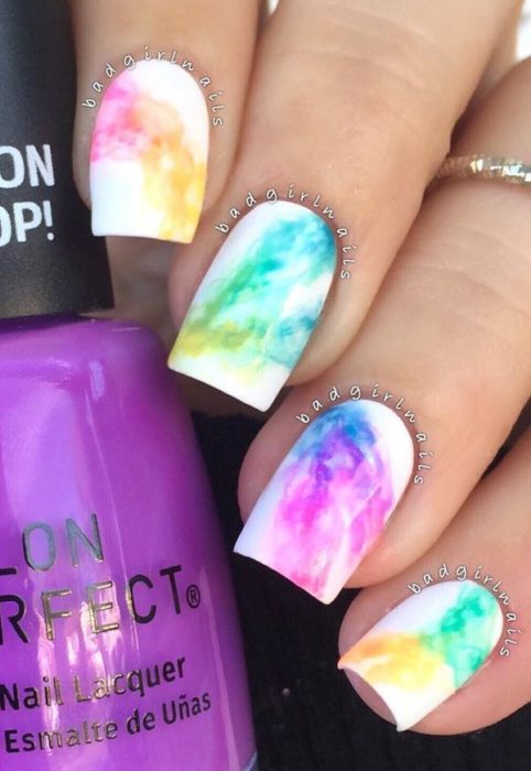 Manicura estilo tie dye en tonos del arcoíris con fondo blanco