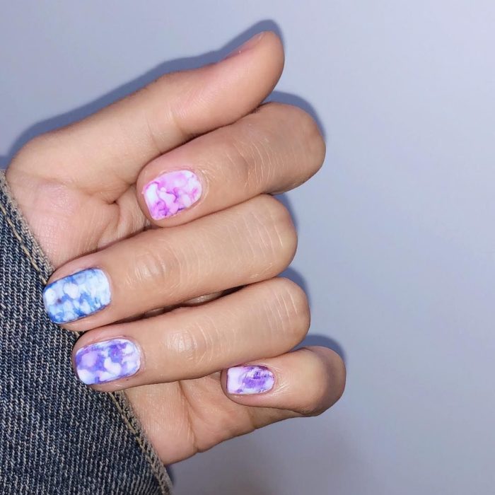 Manicura estilo tie dye de diferentes tonos con fondo blanco