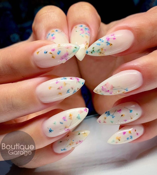 Diseños de manicura milk bath; uñas largas stiletto color blanco con flores rosas, amarillas y azules