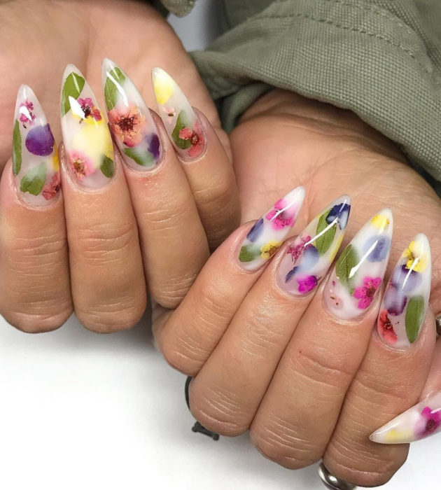 Diseños de manicura milk bath; uñas largas stiletto color blanco con flores moradas, rosas y azules