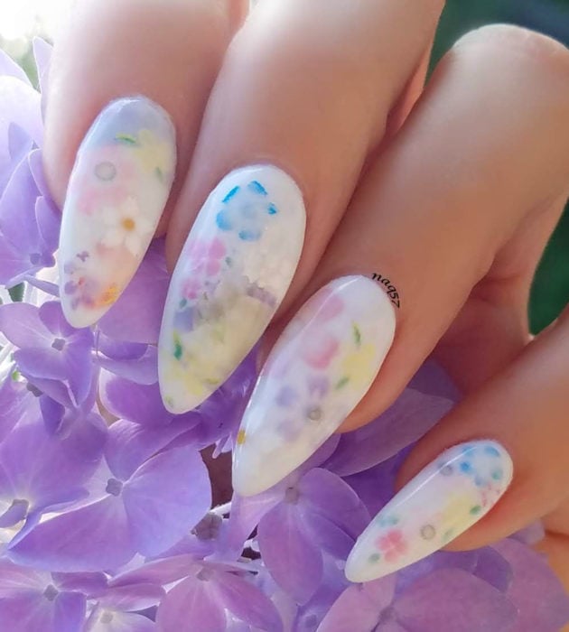 Diseños de manicura milk bath; uñas stiletto largas blancas con flores moradas, azules, amarillas y rosas