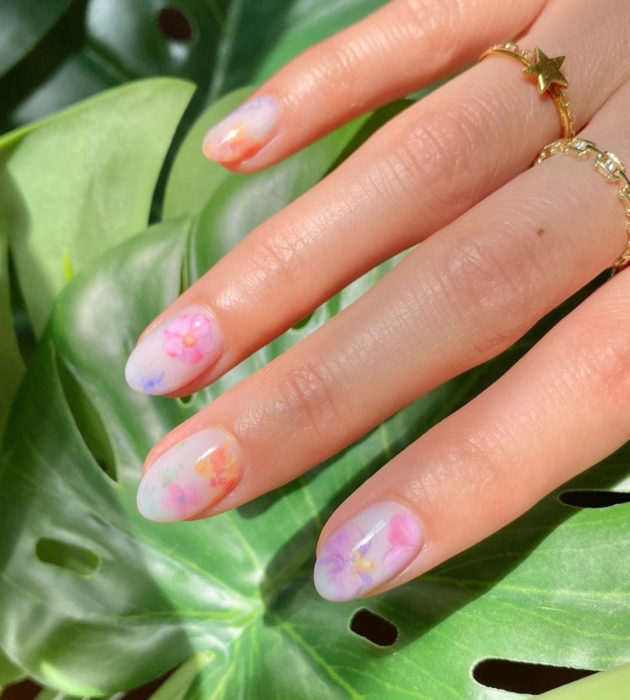 Diseños de manicura milk bath; uñas cortas redondas, blancas con flores rosas, moradas y anaranjadas