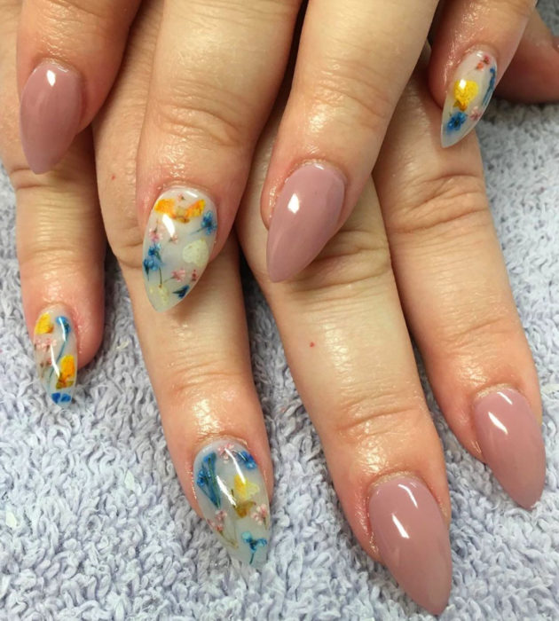 Diseños de manicura milk bath; uñas en forma de almendra, color nude y blanco con flores rosas, azules y amarillas