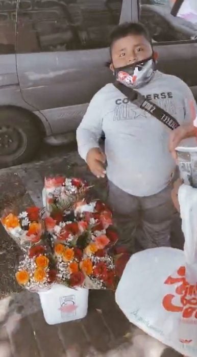 Niño vendiendo flores en una avenida pública