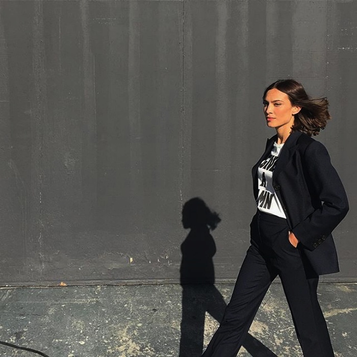 chica de cabello corto usando una camiseta blanca, saco negro y pantalones negros de vestir