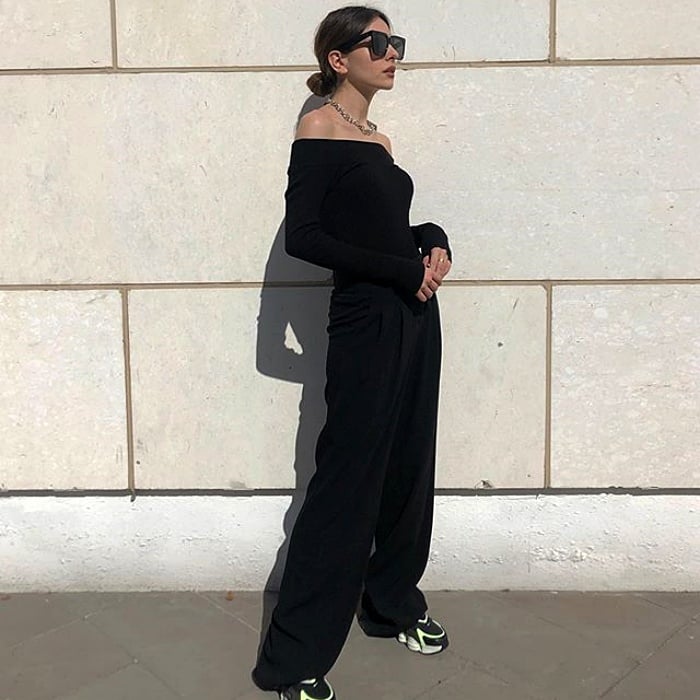 chica de cabello negro con lentes de sol usando un crop top negro de manga larga, pantalon de vestir negro