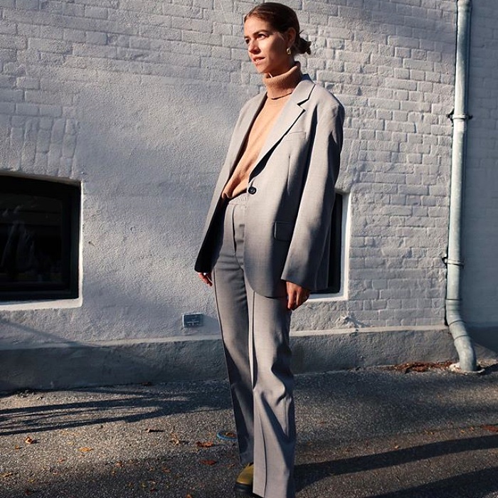 chica rubia usando un top beige, blazer gris y pantalon gris de vestir