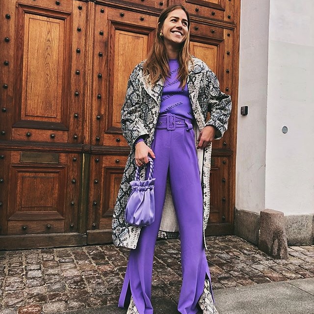 chica de cabello castaño con top morado, saco de animal print, bolso de seda lila, pantalones de vestir morados