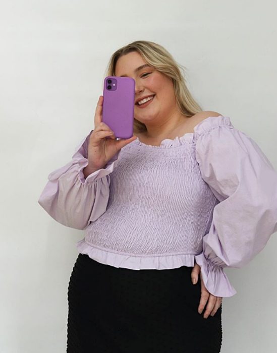 chica curvy rubia usando una blusa color lila claro y jeans negros