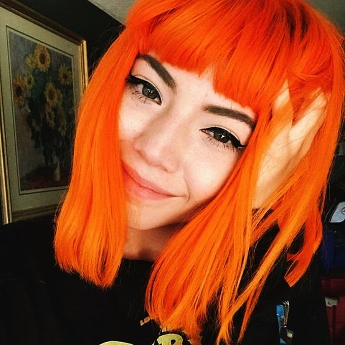 chica con cabello corto y fleco teñido en color anaranjado, naranja neon brillante