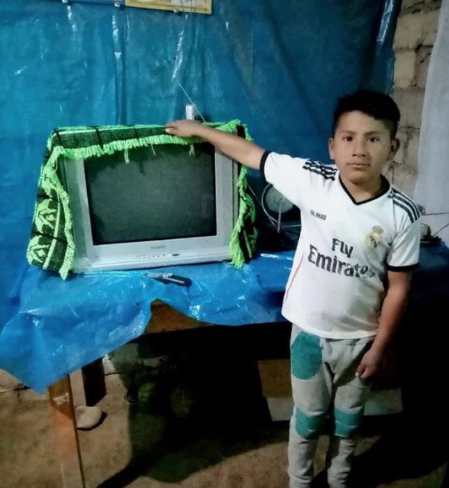 Niño parado al lado de una televisión